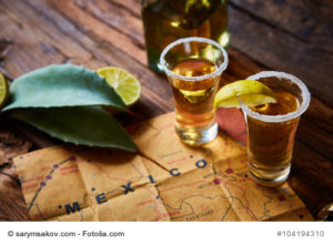 Tequila shot with lime and sea salt on wooden table, selective focus